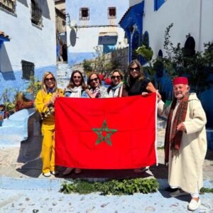Group of travelers holding Moroccan flag in Chefchaouen during 5 Days Tour from Casablanca