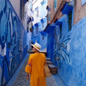 Woman walking through blue-painted alleyways in Chefchaouen on the 5 Days Tour from Casablanca